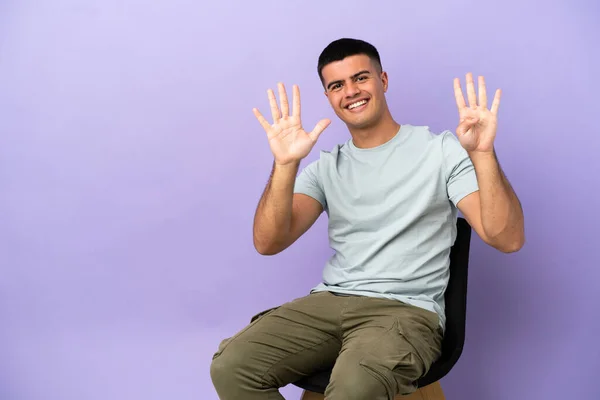 Jovem Sentado Uma Cadeira Sobre Fundo Isolado Contando Nove Com — Fotografia de Stock