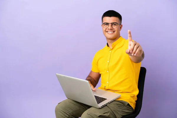 Genç Adam Dizüstü Bilgisayarla Bir Sandalyede Oturuyor Parmağını Kaldırıyor — Stok fotoğraf