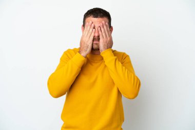 Genç Brezilyalı bir adam beyaz arka planda izole edilmiş, gözleri elle kapatılmış.