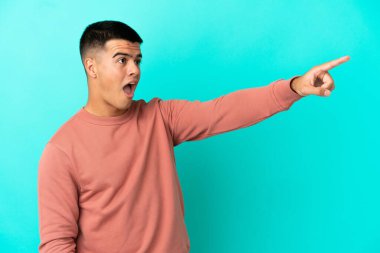 Soyutlanmış mavi arka planı olan yakışıklı bir genç.