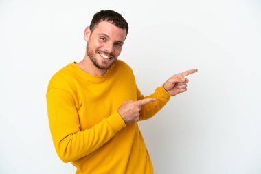 Beyaz arka planda izole edilmiş genç Brezilyalı adam şaşırmış ve işaret ediyor.