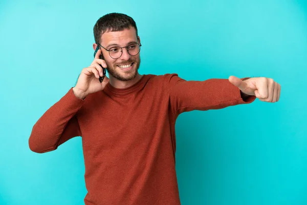 Young Brazilian Man Using Mobile Phone Isolated Blue Background Giving — Stock Photo, Image