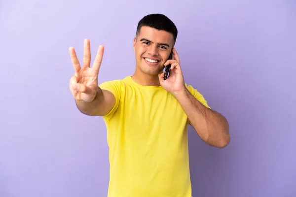 Молодий Красивий Чоловік Використовує Мобільний Телефон Над Ізольованим Фіолетовим Тлом — стокове фото