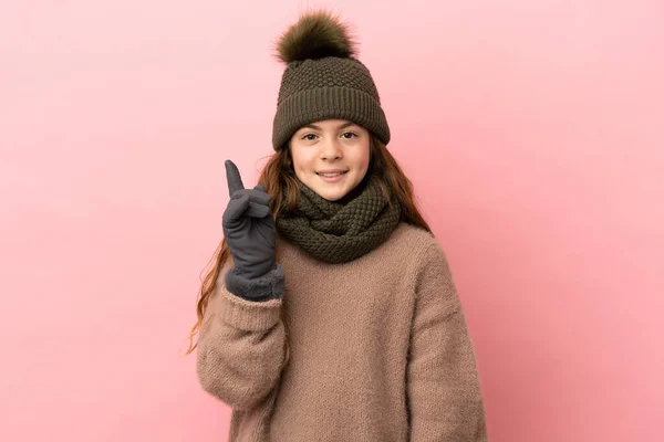 Liten Flicka Med Vinter Hatt Isolerad Rosa Bakgrund Pekar Upp — Stockfoto