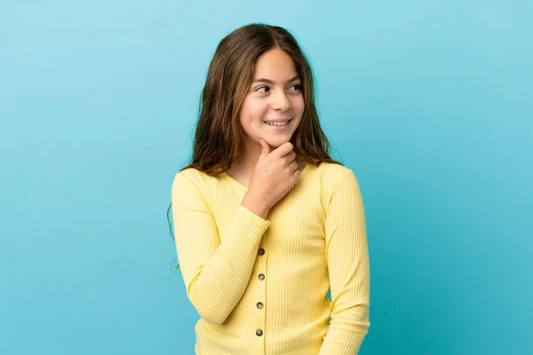 Pequena Menina Caucasiana Isolado Fundo Azul Olhando Para Lado Sorrindo — Fotografia de Stock