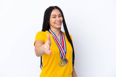 Saçları örgülü ve madalyalı genç bir kız pembe arka planda iyi bir anlaşma yaptığı için el sıkışıyor.