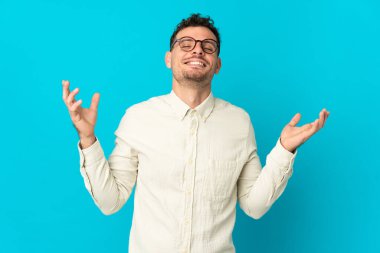 Beyaz tenli yakışıklı bir adam mavi arka planda izole edilmiş, gülümsüyor.