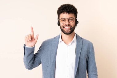 Faslı bir pazarlamacı bej arka planda izole edilmiş bir kulaklıkla harika bir fikre işaret ediyor.