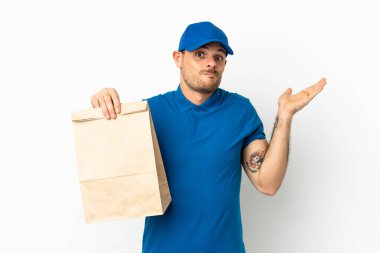 Brezilyalı, beyaz arka planda izole edilmiş bir paket yiyecek alıyor. El kaldırırken şüpheleri var.