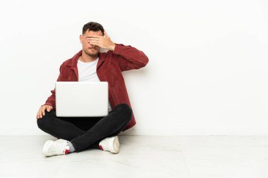 Genç, yakışıklı, beyaz bir adam dizüstü bilgisayarı ve elleri ile yerde oturuyor. Bir şey görmek istemiyorum.