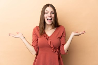 Yüzünde şok ifadesi olan bej bir arka planda izole edilmiş beyaz bir kadın.