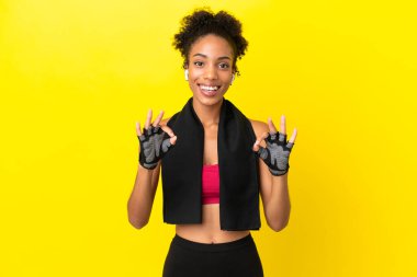 Sarı arka planda izole edilmiş genç Afrikalı spor kadını parmaklarıyla 