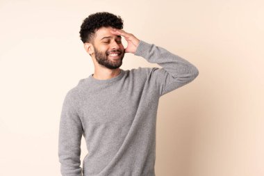 Bej arka planda izole edilmiş genç Faslı adam çok gülümsüyor.