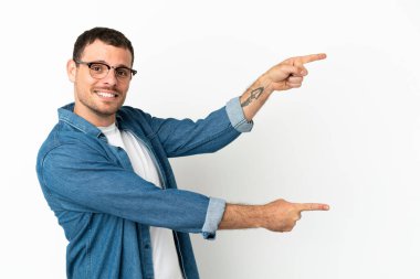 İzole edilmiş beyaz arkaplan üzerinde Brezilyalı bir adam parmak işareti yapıyor ve bir ürün sunuyor