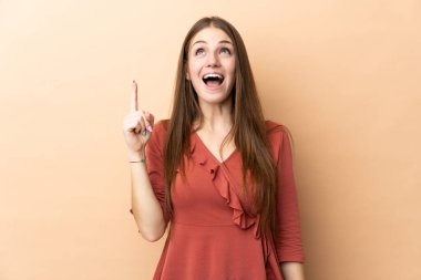 Beyazlı genç bir kadın bej arka planda izole edilmiş ve şaşırmış.