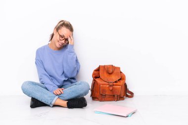 Genç kız beyaz arka planda tek başına oturmuş gülüyor.