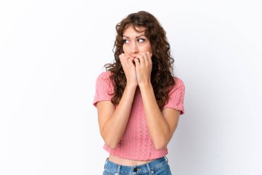 Beyaz arka planda, kıvırcık saçlı, gergin ve korkmuş genç bir kadın.