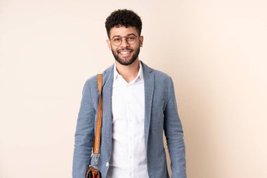 Genç Faslı iş adamı bej arka planda gözlüklü ve mutlu.