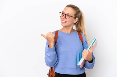 Beyaz arka planda izole edilmiş genç beyaz kadın bir ürünü sunmak için kenarı işaret ediyor.