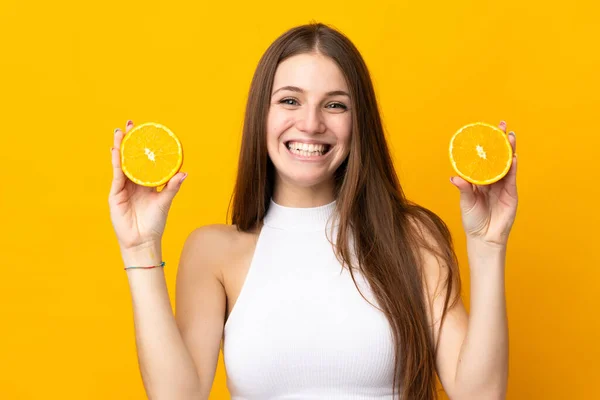 Junge Kaukasische Frau Hält Eine Orange Auf Orangefarbenem Hintergrund — Stockfoto