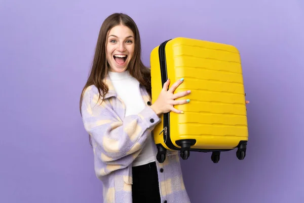 年轻的高加索女人带着旅行箱 穿着紫色背景的衣服 带着令人惊讶的东西外出度假 — 图库照片