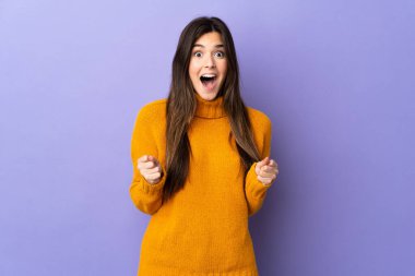 Mor arka planda kalan Brezilyalı genç kız galibiyeti kutluyor.