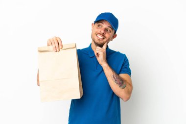 Brezilyalı bir paket yiyecek alıyor beyaz arka planda izole edilmiş bir şekilde yukarı bakarken bir fikir düşünüyor