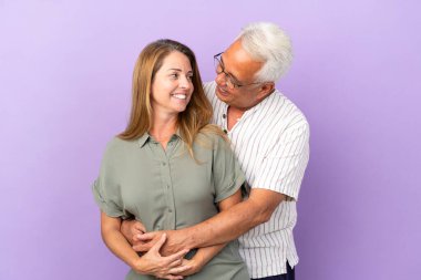 Mor arka planda sarılan orta yaşlı çift.