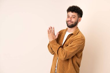 Faslı genç bir adam bej arka planda izole edilmiş bir şeyler planlıyor.