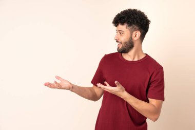 Faslı genç bir adam bej arka planda izole edilmiş.