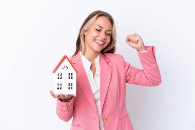 Rus emlakçı elinde oyuncak bir ev tutuyor beyaz arka planda zaferi kutluyor.