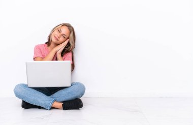 Yerde dizüstü bilgisayarı olan genç bir Rus kız beyaz arka planda izole bir şekilde uyuyor.