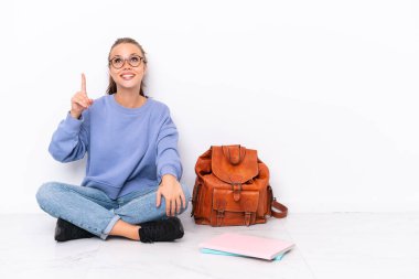 Genç kız beyaz arka planda izole bir zeminde oturuyor ve şaşırmış görünüyor.