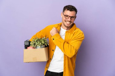 Mor arka planda izole edilmiş bir kutu dolusu şeyi alıp zaferi kutlayan beyaz bir adam hamle yapıyor.