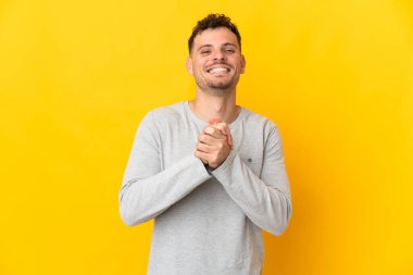 Sarı arka planda izole edilmiş genç beyaz yakışıklı adam gülüyor.