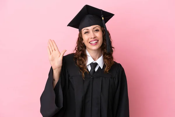 Νεαρή Απόφοιτος Πανεπιστημίου Γυναίκα Απομονωμένη Ροζ Φόντο Χαιρετισμό Χέρι Χαρούμενη — Φωτογραφία Αρχείου