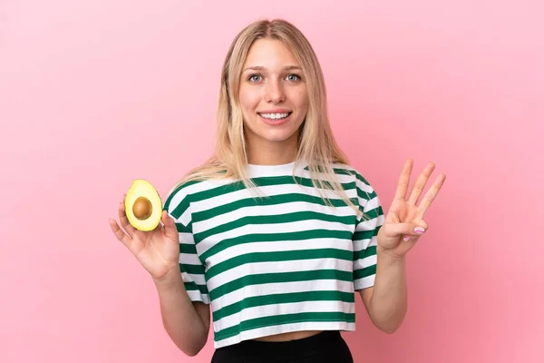 Junge Kaukasische Frau Hält Eine Avocado Isoliert Auf Rosa Hintergrund — Stockfoto