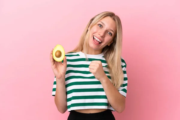 Junge Kaukasische Frau Mit Einer Avocado Auf Rosa Hintergrund Feiert — Stockfoto