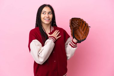 Beyzbol eldivenli genç oyuncu pembe arka planda izole edilmiş gülümserken yukarı bakıyor