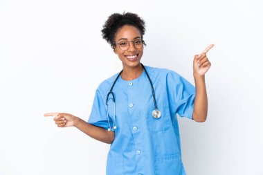 Genç cerrah Afrikalı Amerikalı kadın izole edilmiş beyaz arka planda parmak uçlarını işaret ediyor ve mutlu.