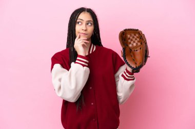 Beyzbol eldivenli genç oyuncu pembe arka planda izole edilmiş, yukarı bakarken şüpheleri var.