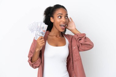 Genç Afrikalı Amerikalı bir kadın, beyaz arka planda izole edilmiş bir sürü para alıyor. Kulağına elini sürerek bir şeyler dinliyor.