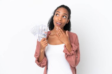 Genç Afrikalı Amerikalı bir kadın çok para alıyor. Beyaz arka planda izole edilmiş. Gülümserken yukarı bakıyor.