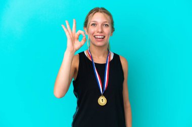 Mavi arka planda madalyalı beyaz bir kadın parmaklarıyla işaret veriyor.