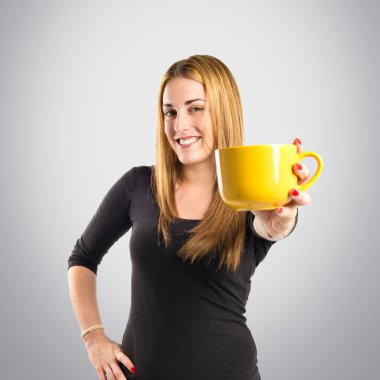 Gri arka planda bir fincan kahve tutan güzel kız. 