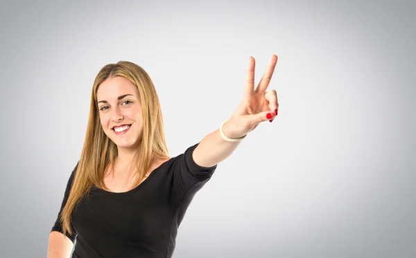 Chica rubia haciendo gesto de victoria sobre fondo gris —  Fotos de Stock