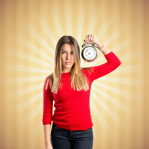 Chica joven sosteniendo un reloj antiguo sobre fondo pop — Foto de Stock