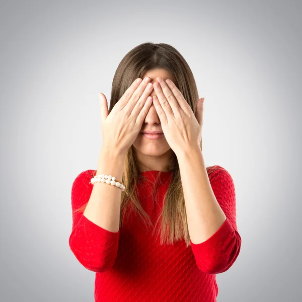 Young girl covering her eyes over grey background — Stock Photo, Image
