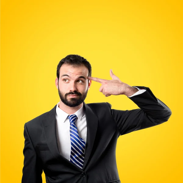 Young businessman committing suicide over yellow background — Stock Photo, Image