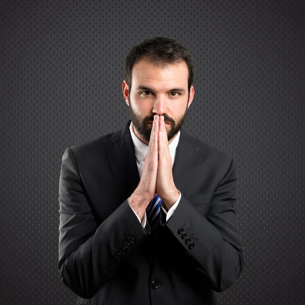 Joven hombre de negocios suplicando sobre fondo negro — Foto de Stock